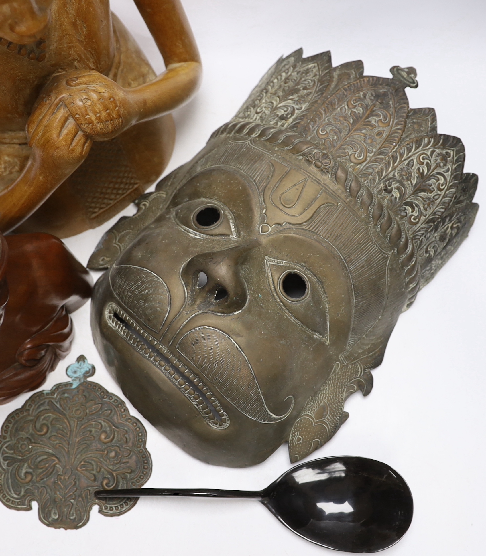 A West African carving of a girl, and a Balinese bust of a man together with an Indonesian metal mask and black lacquered spoon, mask 38cm high